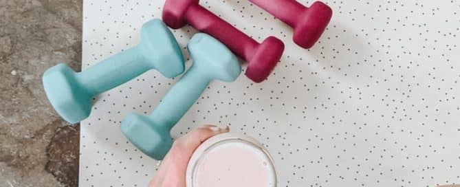 Person sitting on mat with weights and a smoothie