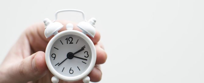 hand holding mini alarm clock