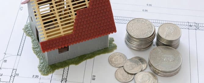 house and coins sitting on a floor plan