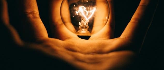 hand holding a glowing lightbulb