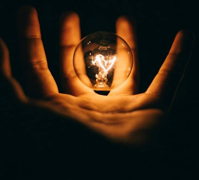 hand holding a glowing lightbulb