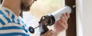 man caulking a window