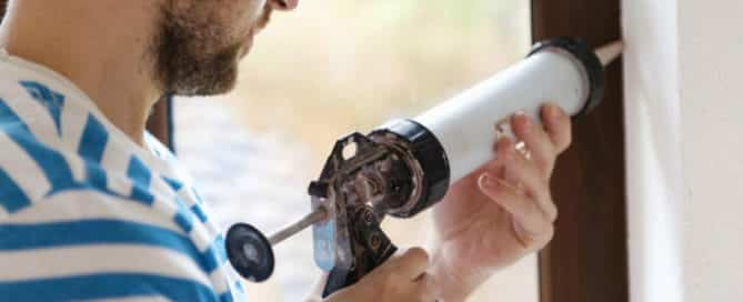 man caulking a window