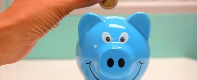 Person putting coins in a blue piggy bank