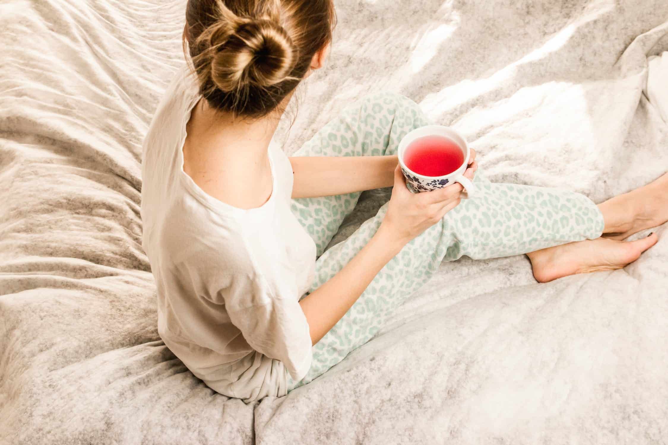 Woman sitting on the bed with a cup of tea