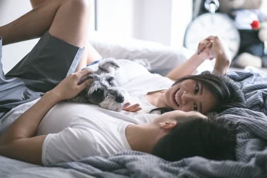 Couple laying on the bed with their dog