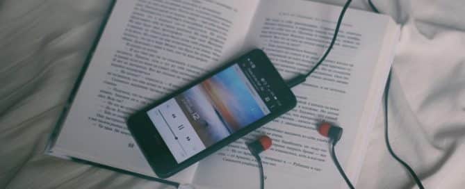 Smart phone playing music, with headphones plugged in, wrapped around a book
