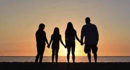 Silhouette family holding hands on the beach in front fo the sunset