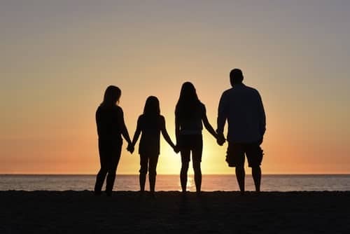 Silhouette family holding hands on the beach in front fo the sunset