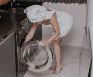 woman in bath towel reaching into a dryer